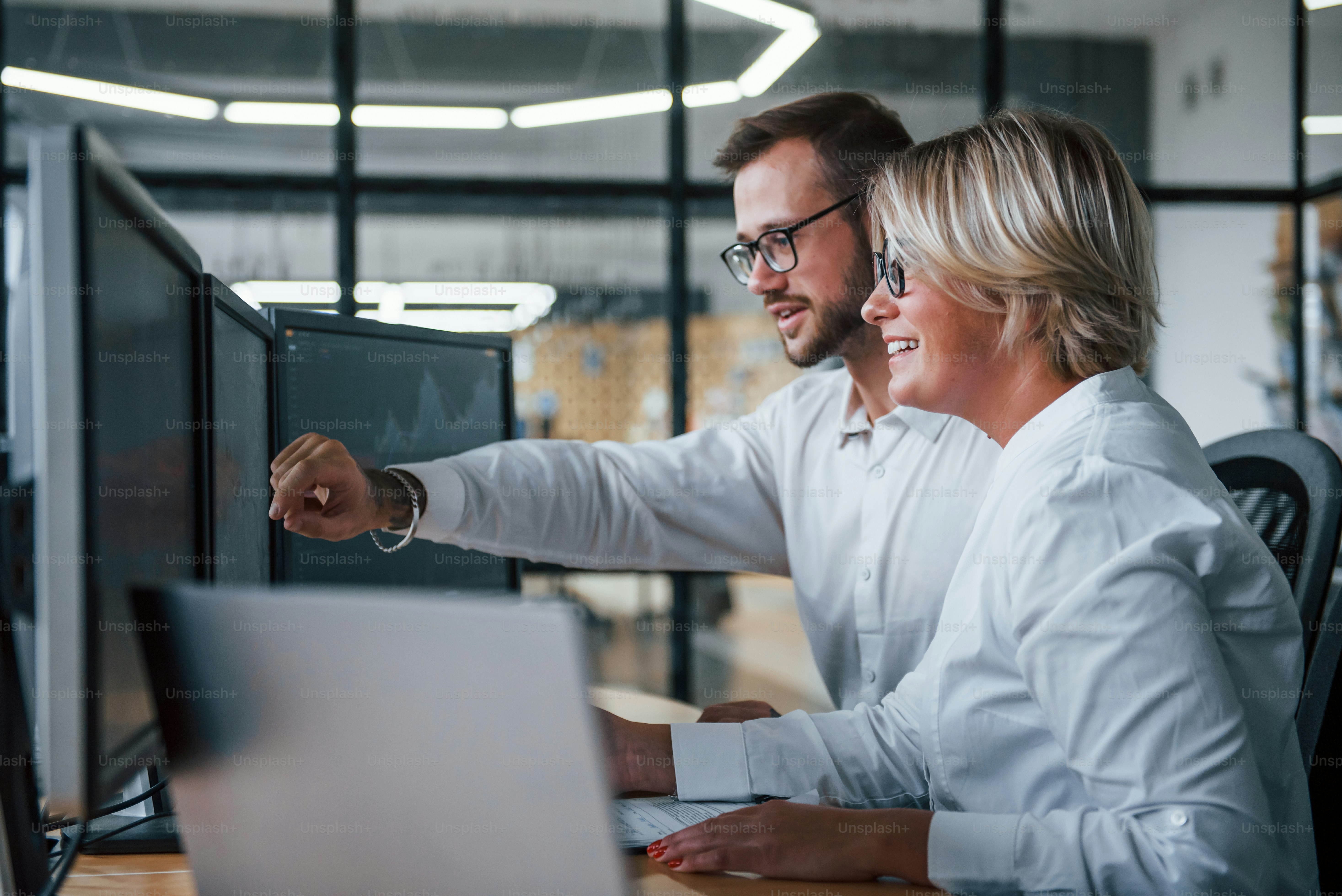 Dos corredores de bolsa con ropa formal trabajan en la oficina con el mercado financiero.