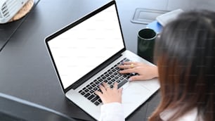 Joven contadora se concentra trabajando en una computadora portátil en el escritorio de su oficina.