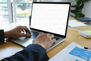 Gros plan d’une femme d’affaires travaillant avec un ordinateur portable et analysant des documents à son bureau.