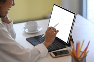 Young female creative designer holding using stylus pen drawing on computer tablet while sitting in office.