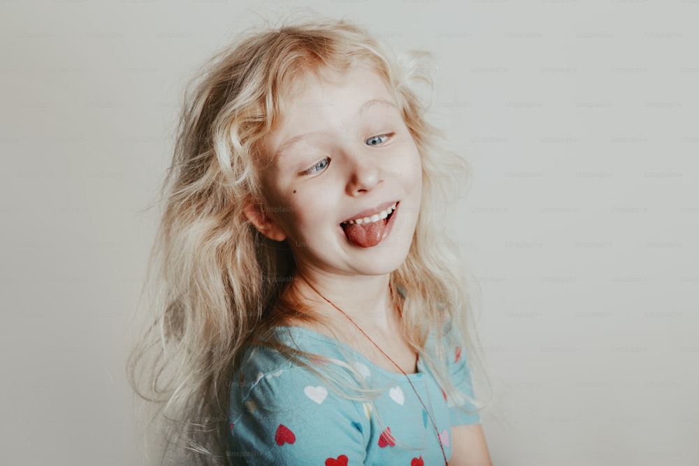 Cross-eyed Caucasian blonde girl looking at her nose. Funny hilarious preschool kid making silly face. Cute adorable child having fun. Crazy weird girl portrait. Happy childhood lifestyle.