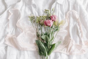 Stylish lace lingerie and spring flowers on shirt on bed. Soft trendy feminine image, sensual mood at home concept. Happy Women's day. Woman essentials, fragrance