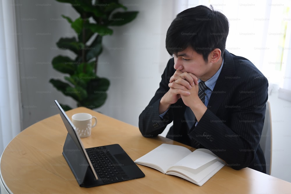 Hombre de negocios serio mirando la tableta de la computadora mientras está sentado en su lugar de trabajo.