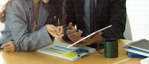 Foto cortada de empresários discutindo sobre sua estratégia de negócios com tablet digital e papelada