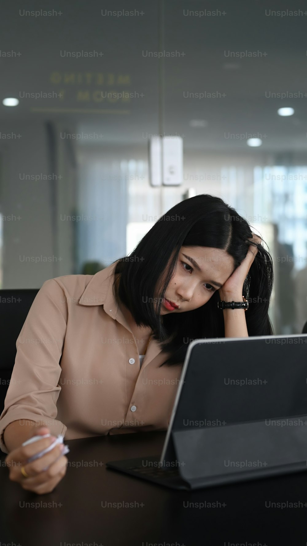 Jovem trabalhadora de escritório segurando a cabeça e sofrendo estresse trabalhando.
