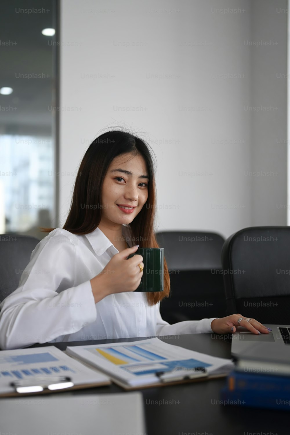 Portrait d’une femme d’affaires attrayante tenant une tasse de café et souriant à la caméra.