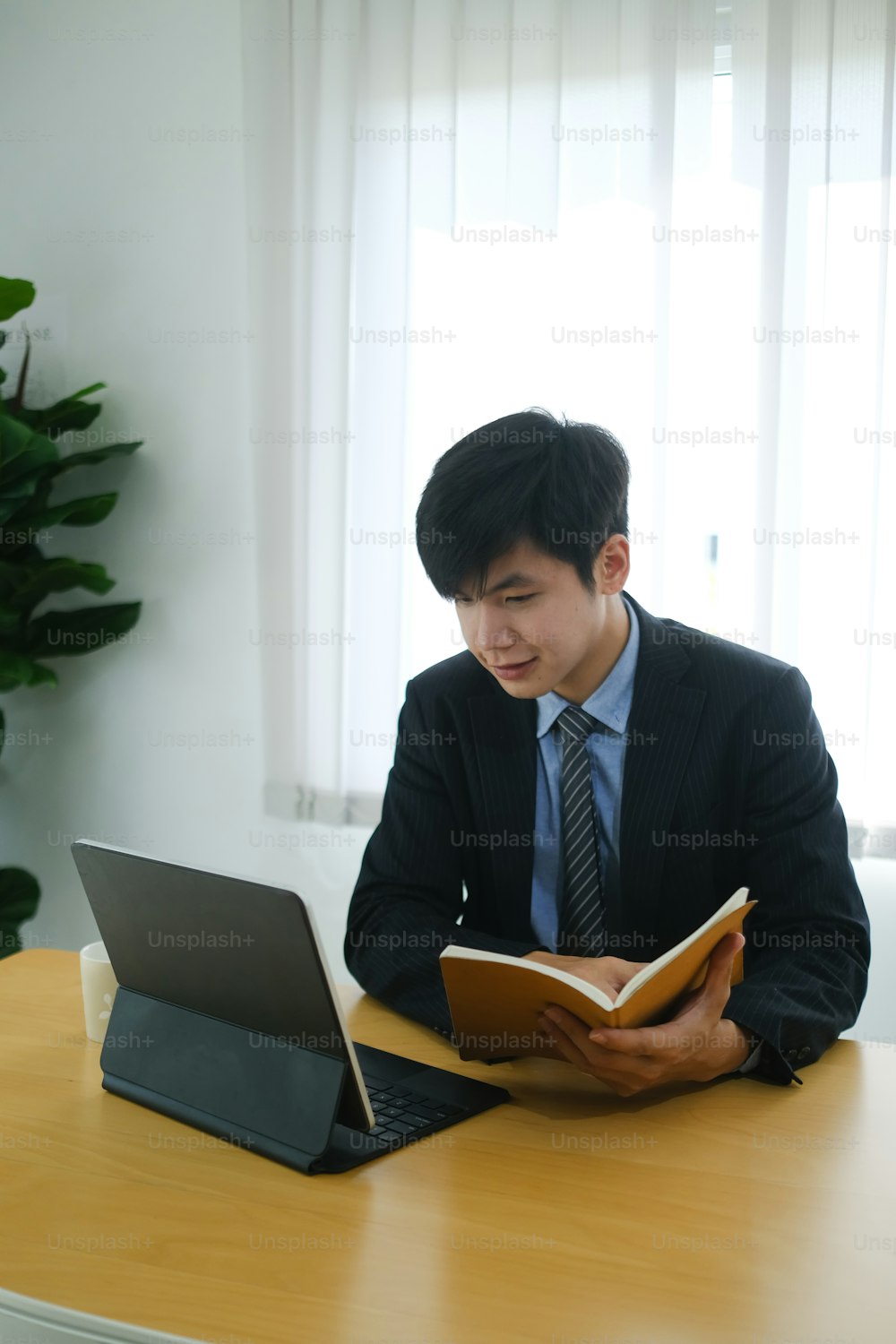Portrait of attractive businessman holding notebook and looking on screen of computer tablet.