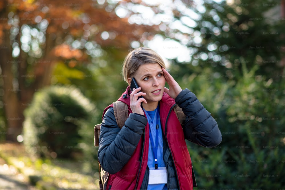 Portrait d’une aide-soignante, d’une infirmière ou d’une travailleuse de la santé à l’extérieur sur le chemin du travail, à l’aide d’un smartphone.