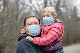 Caucasian father with child girl wearing sanitary face masks outdoor. Family dad and daughter protect themselves from dangerous spread of virus. Coronavirus COVID-19 quarantine.