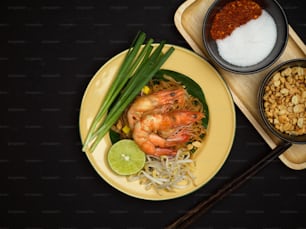 Draufsicht auf gebrannte Thai-Nudeln mit Garnelen mit Limette, Bohnensprossen und Schnittlauch, Pad Thai, thailändisches Essen