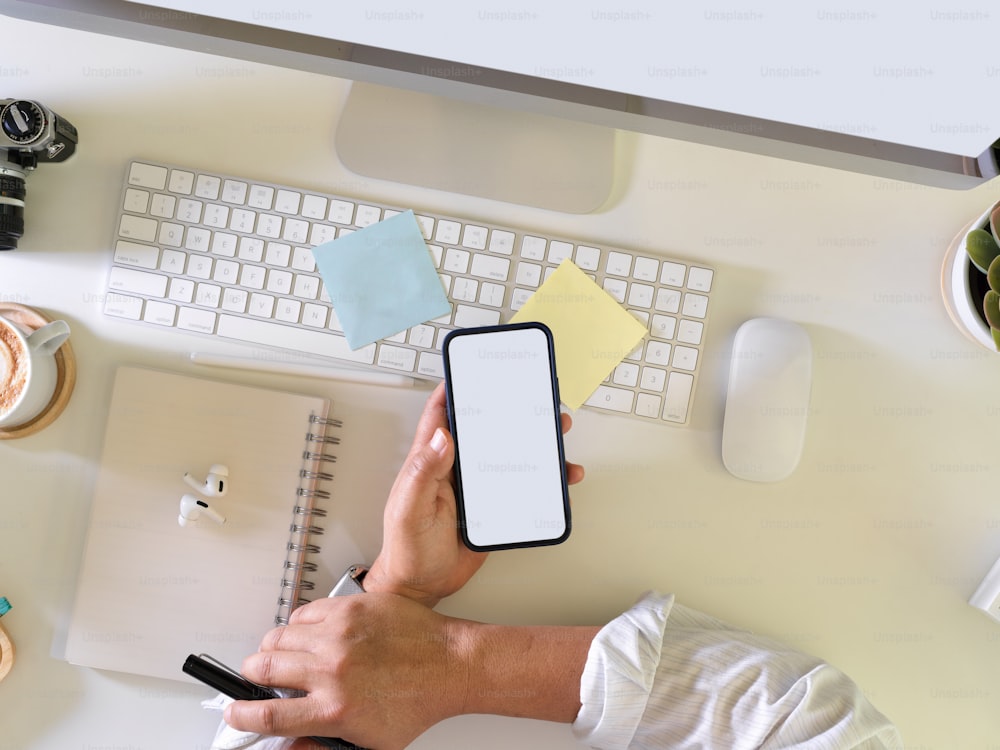Foto aérea de empresário usando smartphone na mão enquanto trabalhava na mesa do computador