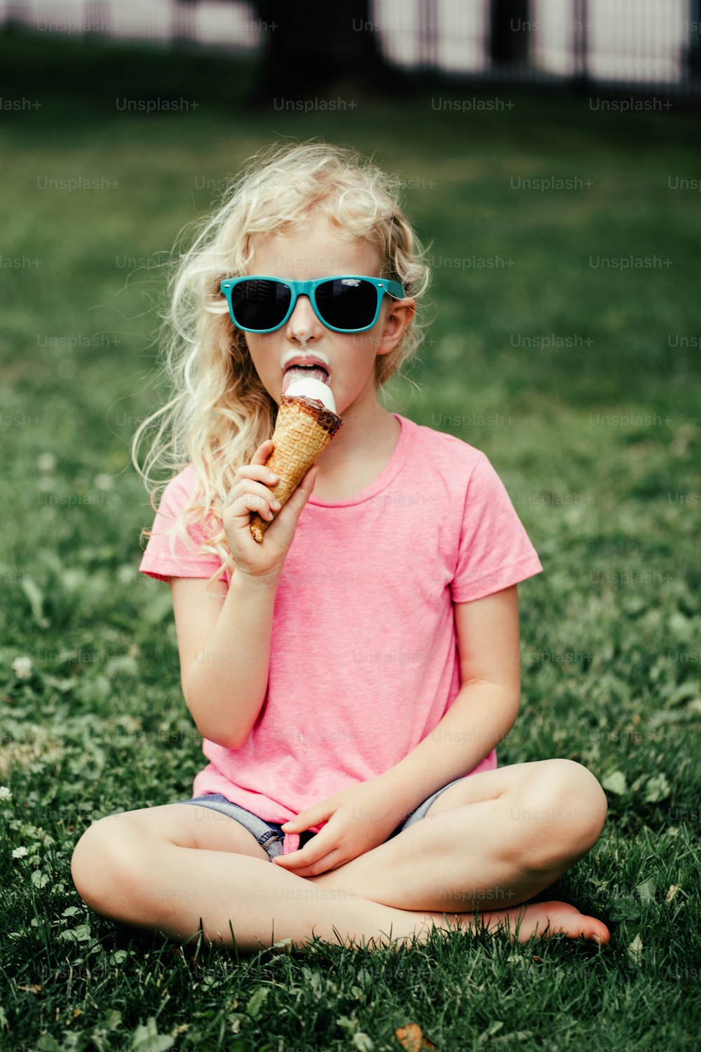 Cute funny adorable girl in sunglasses with dirty nose and moustaches eating ice cream from waffle cone. Happy cool hipster child eating tasty sweet cold summer seasonal food outdoor. Summer fun.