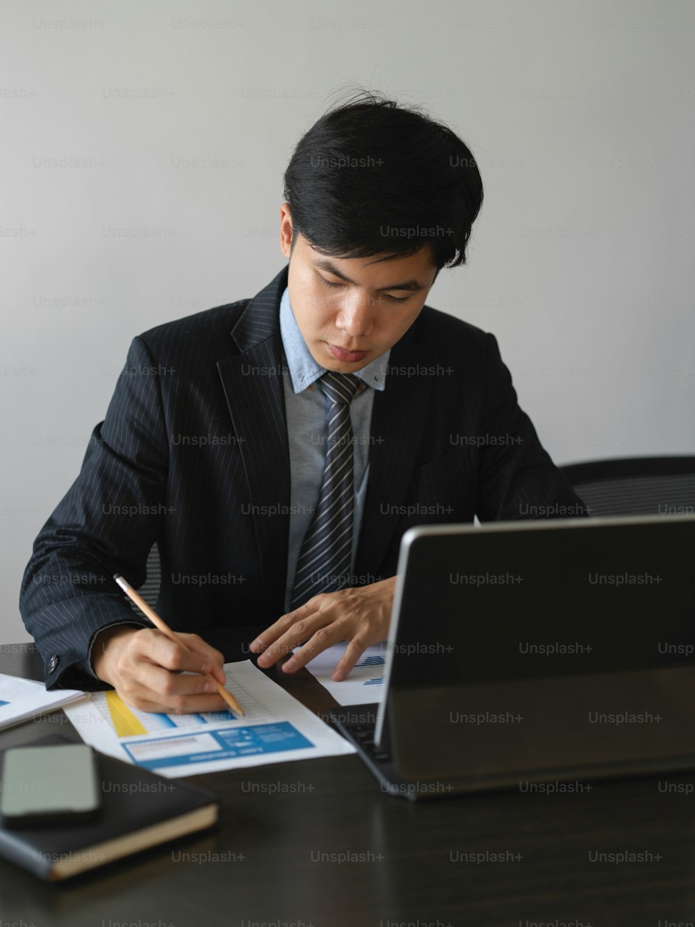 Portrait of businessman analysing on business paperwork on the table with tablet in office room