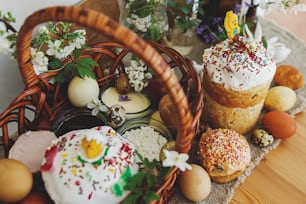 Traditional Easter food for blessing, homemade Easter bread, stylish easter eggs and blooming spring flowers on linen napkin on rustic table. Happy Easter! Festive breakfast