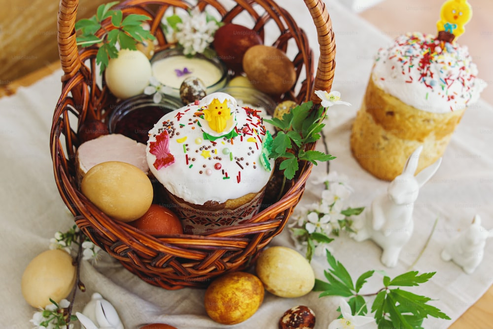Traditionelles Osteressen zum Segen, selbstgebackenes Osterbrot, stilvolle Ostereier und blühende Frühlingsblumen auf Leinenserviette auf rustikalem Tisch. Frohe Ostern! Festliches Frühstück