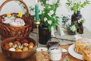 Traditional Easter food for blessing, homemade Easter bread, stylish easter eggs, candle and blooming spring flowers on linen napkin on rustic table. Happy Easter! Festive breakfast