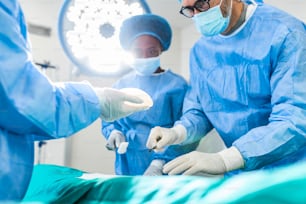 Chirurgien et son assistant effectuant une chirurgie esthétique dans la salle d’opération de l’hôpital. Chirurgien en masque lors de la procadure médicale. Augmentation, agrandissement, rehaussement mammaire
