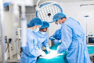手術室で患者を手術する集中外科チーム。複雑な機械を使った長年の訓練を受けたよく訓練された麻酔科医が、手術中ずっと患者をフォローします。