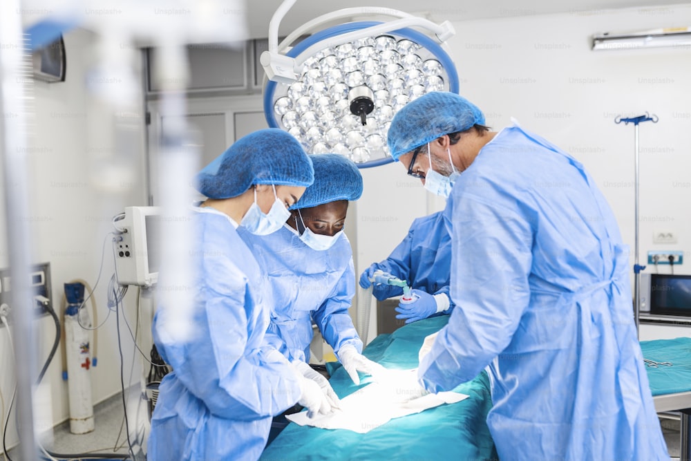 Equipo quirúrgico concentrado operando a un paciente en un quirófano. Un anestesiólogo bien capacitado con años de entrenamiento con máquinas complejas sigue al paciente durante toda la cirugía.