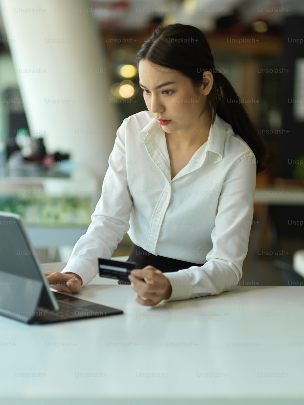 Portrait of young beautiful businesswoman online paying with digital tablet and debit card in her hand