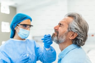 Coronavirus test - Medical worker taking a swab for corona virus sample from potentially infected man. covid-19 nasal swab test - doctor taking a mucus sample from patient nose in hospital