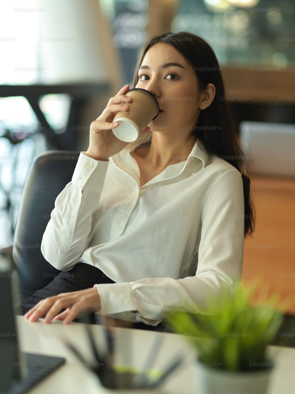 Portrait of businesswoman drinking coffee break while lying relaxed on back chair at workplace