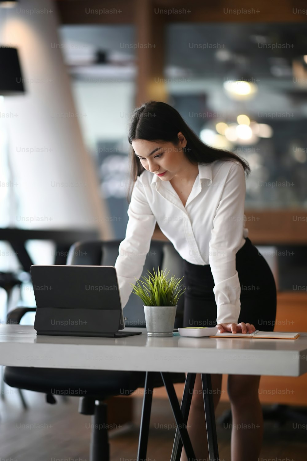Portrait of attractive businesswoman standing at her workplace and working with computer tablet.