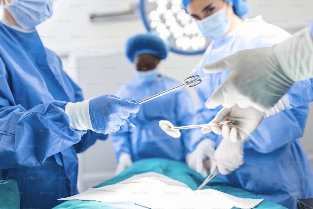 Low Angle Shot in the Operating Room, Assistant Hands out Instruments to Surgeons During Operation. Surgeons Perform Operation. Professional Medical Doctors Performing Surgery.