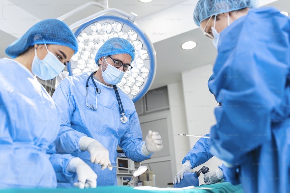 Ein Ärzteteam steht in der Notaufnahme. Multiethnische Chirurgen arbeiten im Operationssaal des Krankenhauses. Sie tragen blaue Peelings.