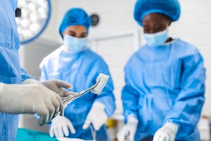 Arzt und Assistenzkrankenschwester operieren für Hilfe Patient aus gefährlichen Notfällen. Chirurgische Instrumente auf dem sterilen Tisch im Notfall-OP im Krankenhaus. Gesundheitswesen und Medizin