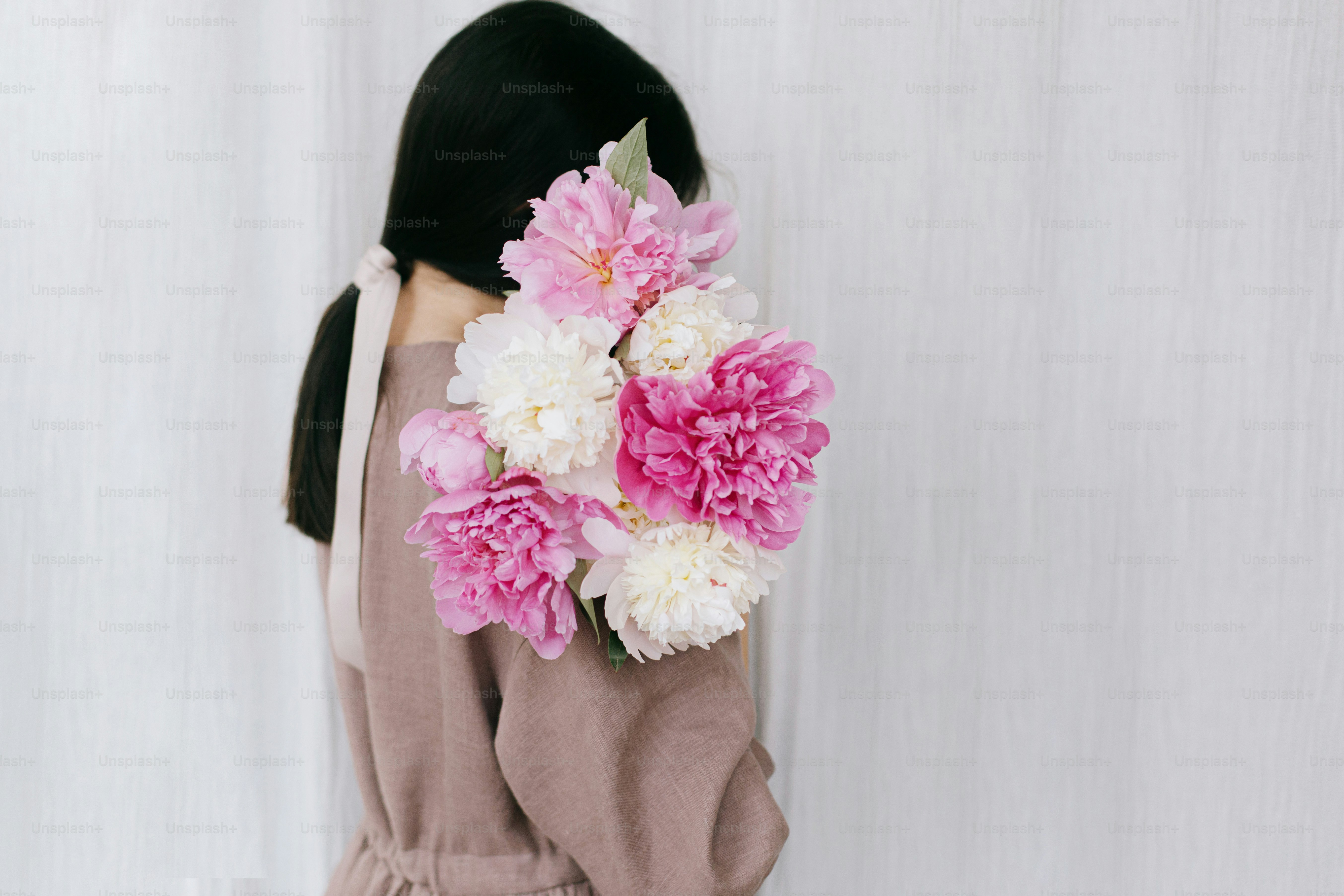 Stylish woman in linen dress holding peony bouquet on background of ...
