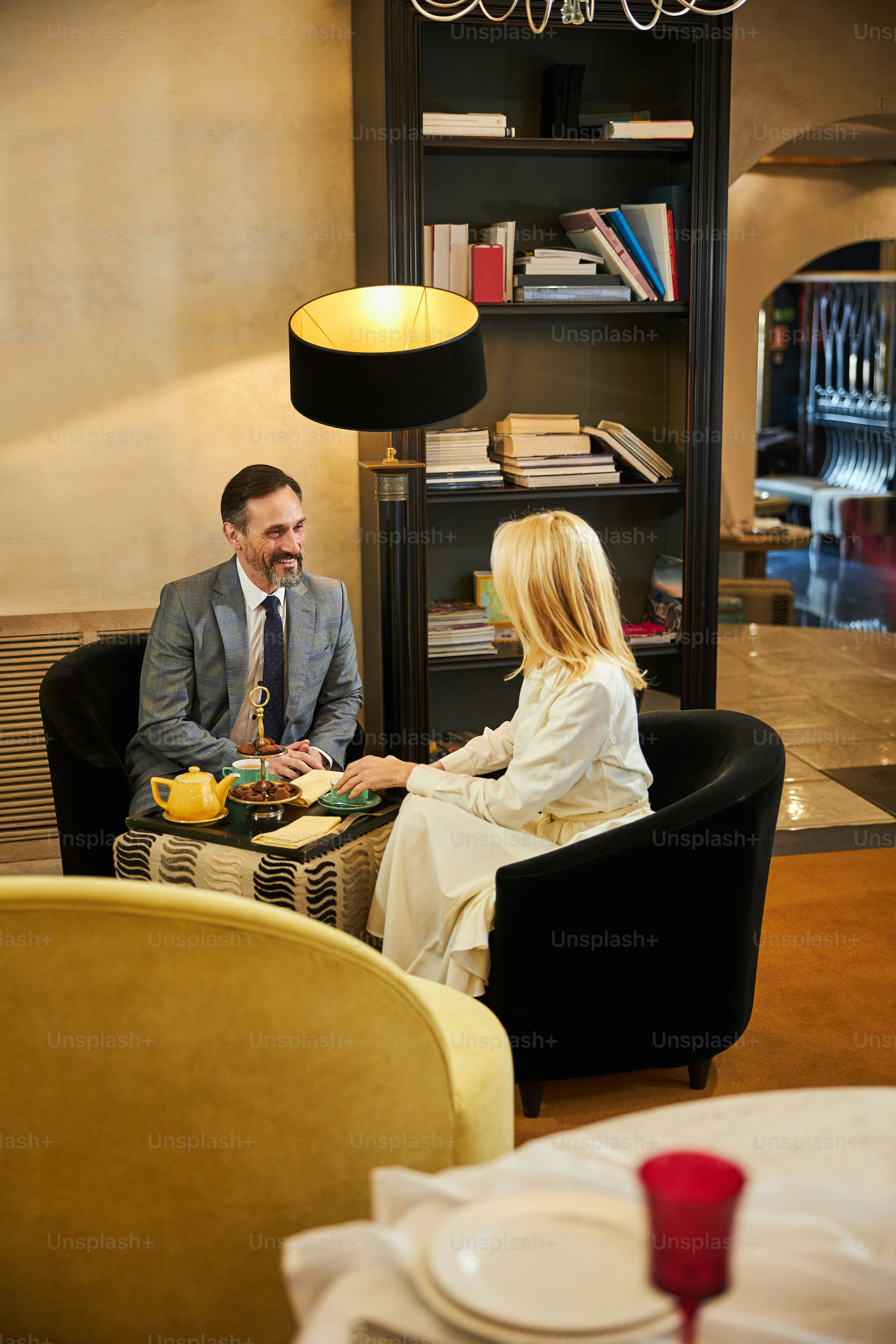 Dressed-up gentleman and his charming woman enjoying each other company at a cozy cafe lounge