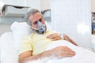 코로나바이러스 covid-19 발생 기간 동안 산소 마스크로 천천히 호흡하는 은퇴한 노인의 초상화. 병원 침대에 누워 치명적인 감염 치료를 받고 있는 늙은 병자