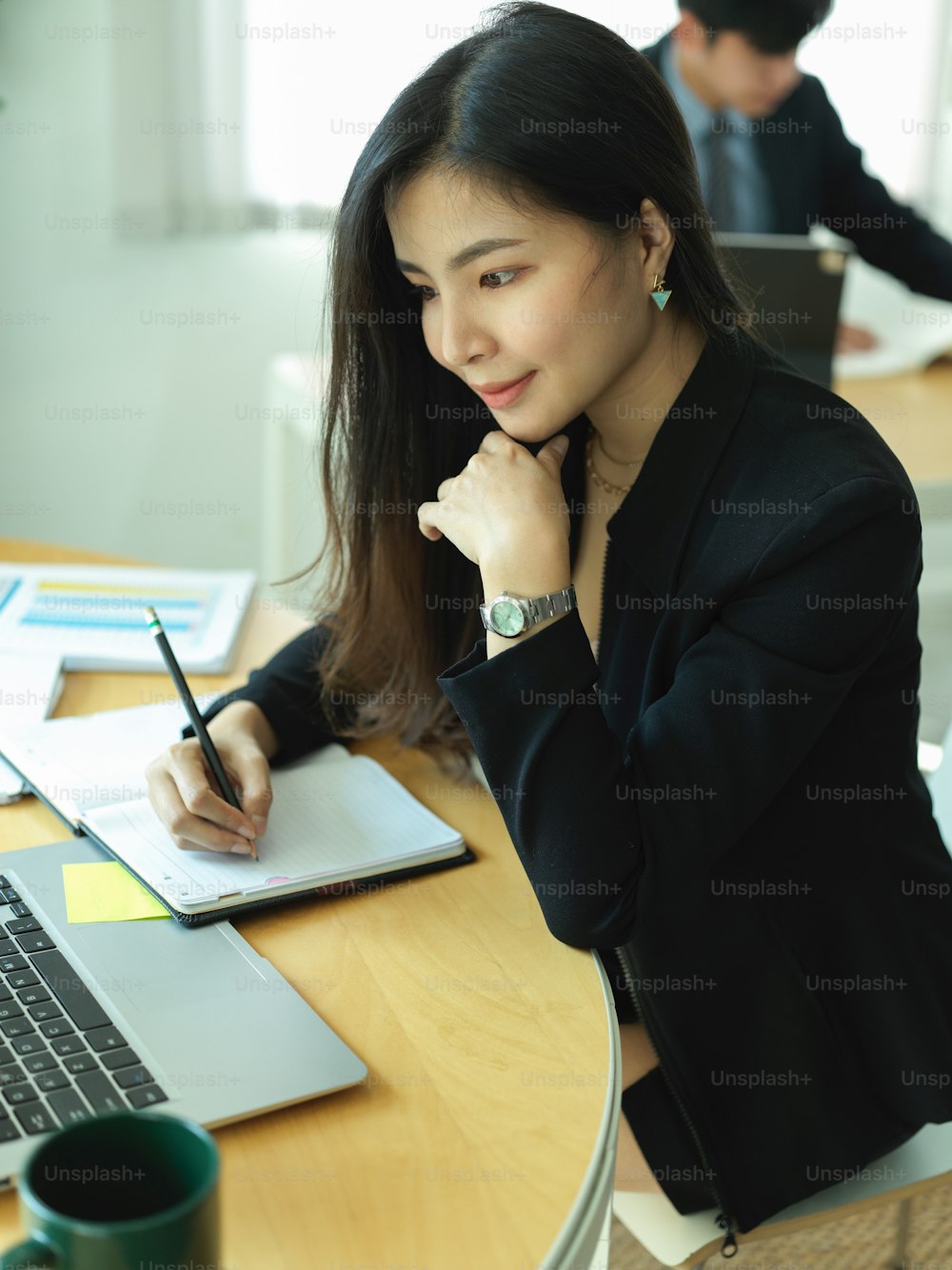Retrato de una mujer de negocios en traje negro concentrándose en su trabajo en la oficina