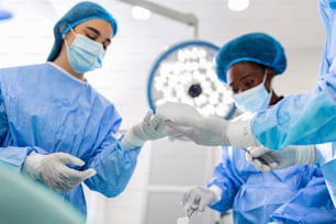 病院の手術室で美容整形を行う外科医とその助手。医療プロカデレーション中のマスク姿の外科医。豊胸、拡大、強化