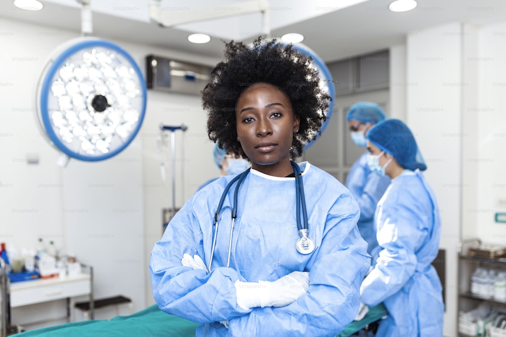 Ritratto di chirurgo afroamericano in piedi in sala operatoria, pronto a lavorare su un paziente. Operatrice sanitaria in uniforme chirurgica in sala operatoria.