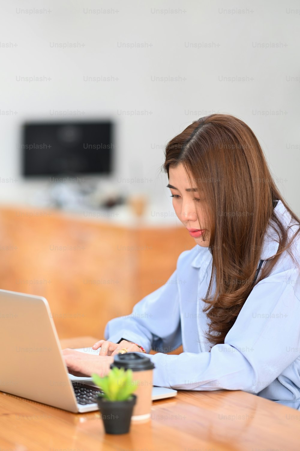 Portrait of young female freelancer working with computer laptop on wooden table.
