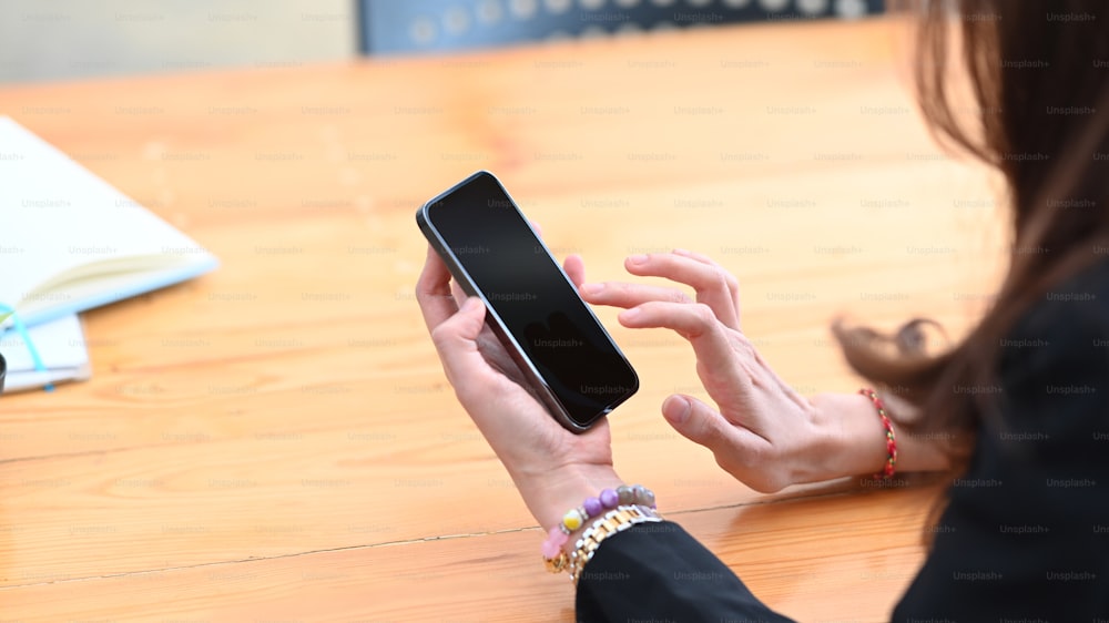 Nahaufnahme junge Frau hält Mock-up-Smartphone mit leerem Bildschirm.