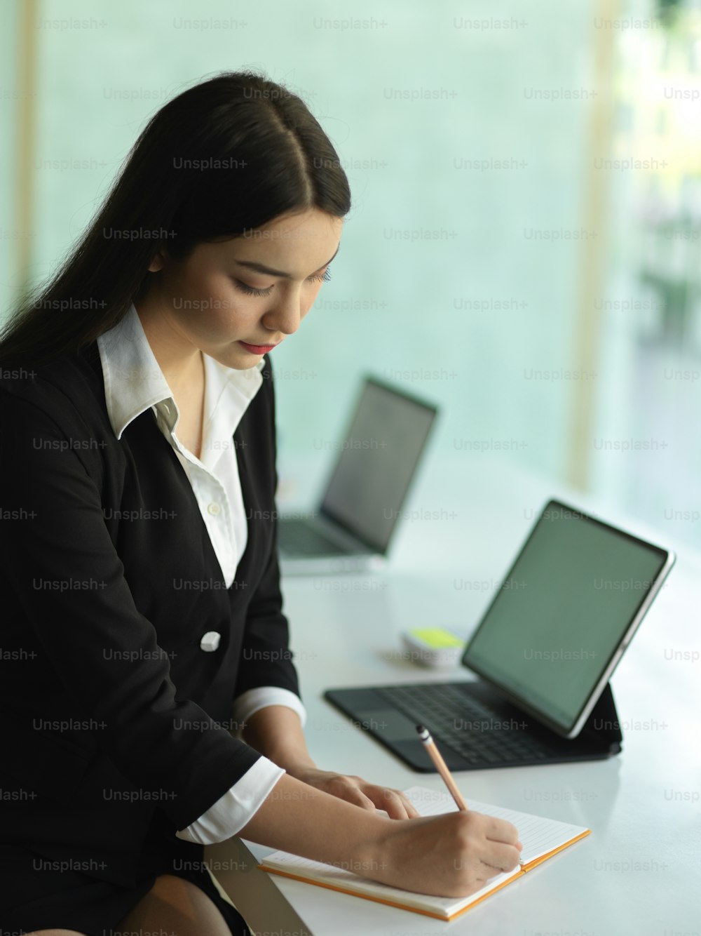 Portrait of female office worker in black suit planing her schedule on office table