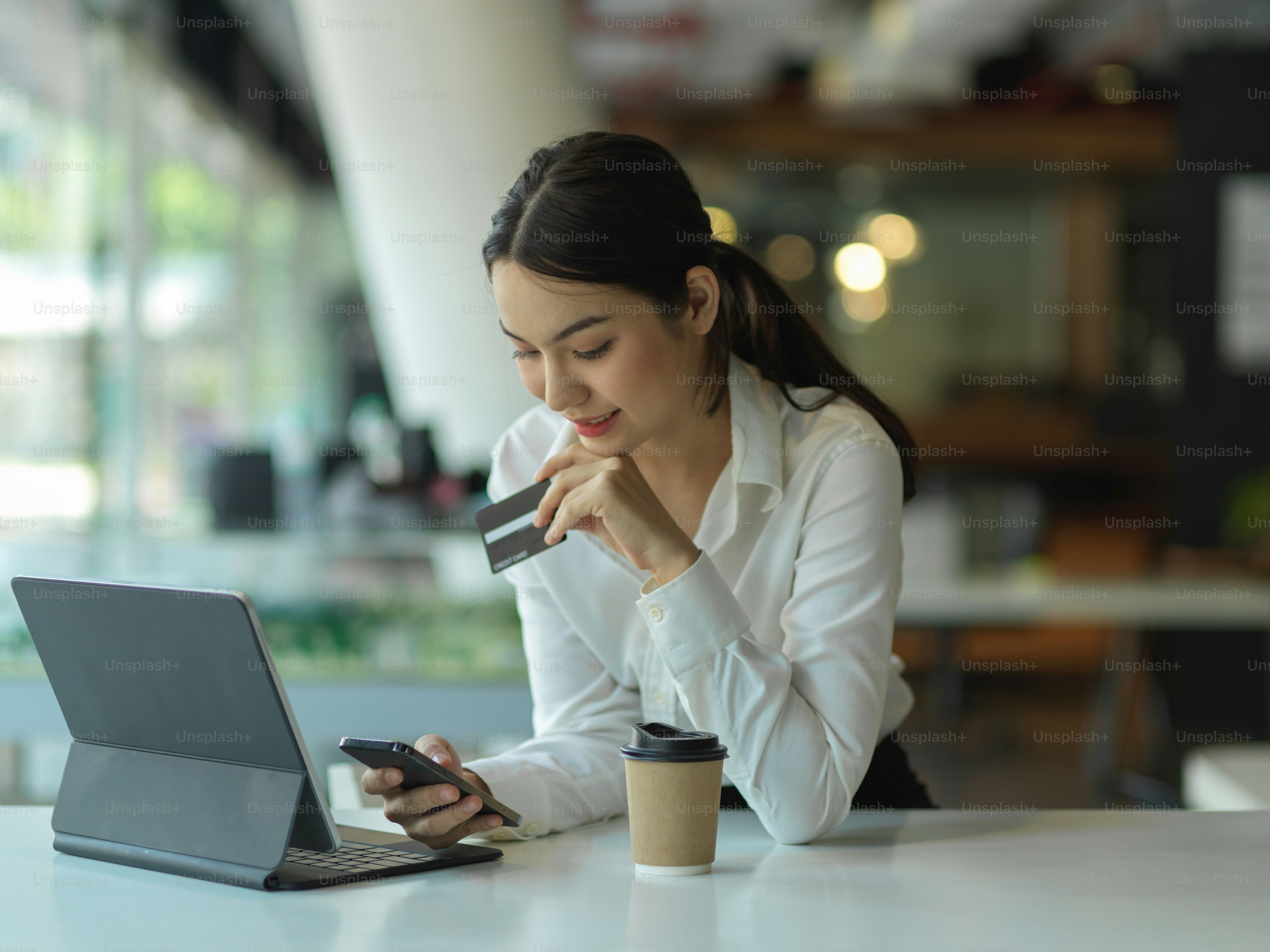 Portrait of happy young female online shopping and paying with credit card on smartphone, online payment concept