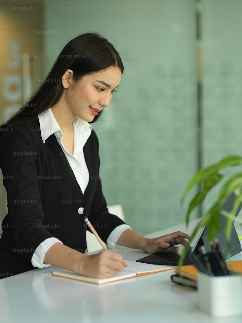 Portrait of businesswoman in black suit working with digital tablet and stationery in office room