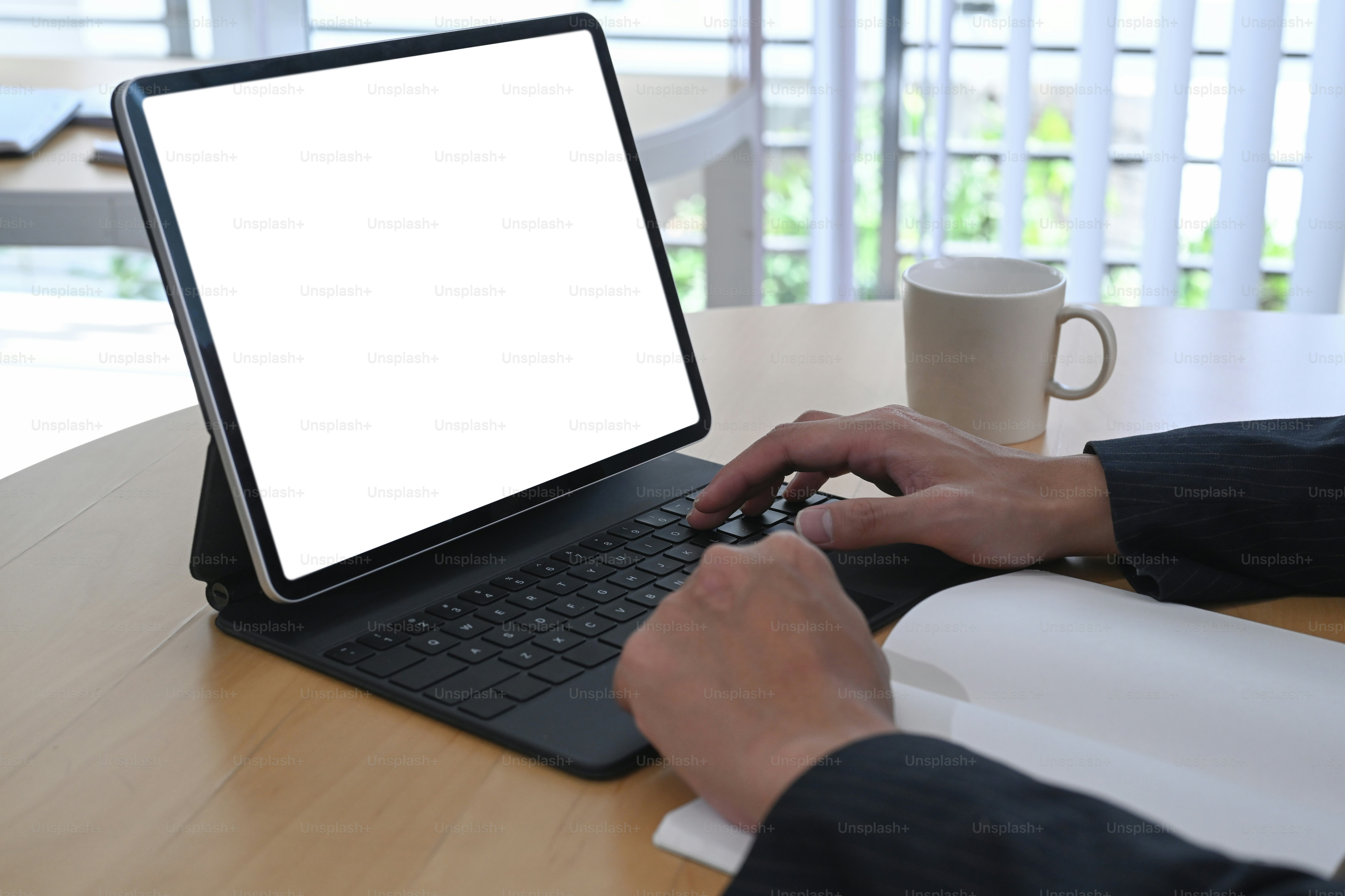 Close up view of businesswoman hands typing on wireless keyboard of digital tablet at wooden office desk.