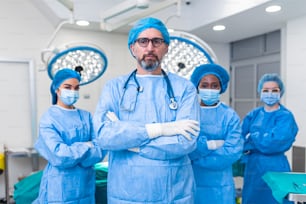 Group of medical surgeons wearing hospital scrubs in operating theatre. Portrait of successful medical workers in surgical uniform in operation theater, ready for next operation.