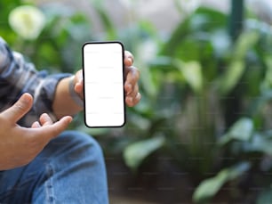 Cropped shot of a man showing mock up smartphone screen to camera with blurred garden background, clipping path