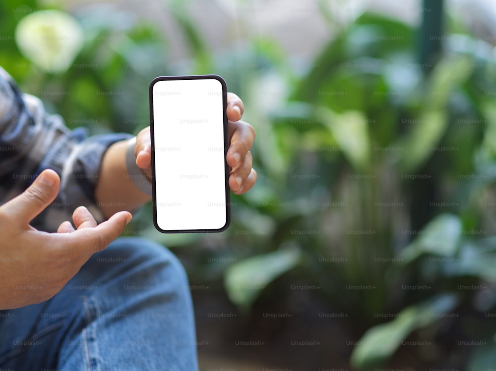 Cropped shot of a man showing mock up smartphone screen to camera with blurred garden background, clipping path