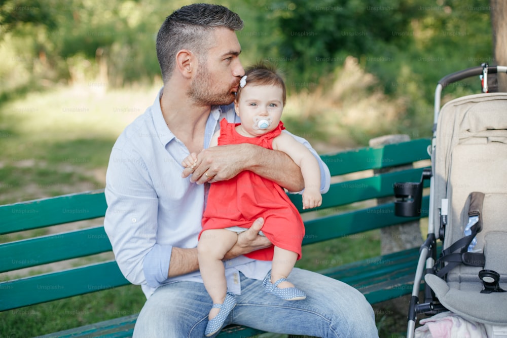 Caucasian proud father holding and kissing baby daughter. Family dad and daughter walking together outdoor in park on summer day. Life with kids children. Happy lifestyle family of two.