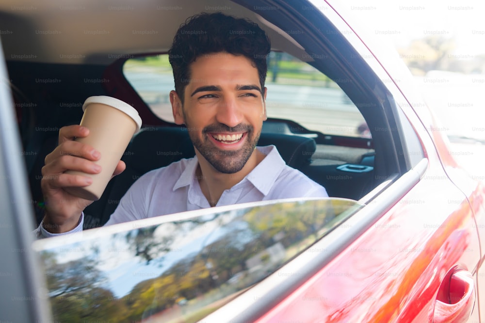 Portrait of businessman drinking coffee on his way to work in car. Business concept.