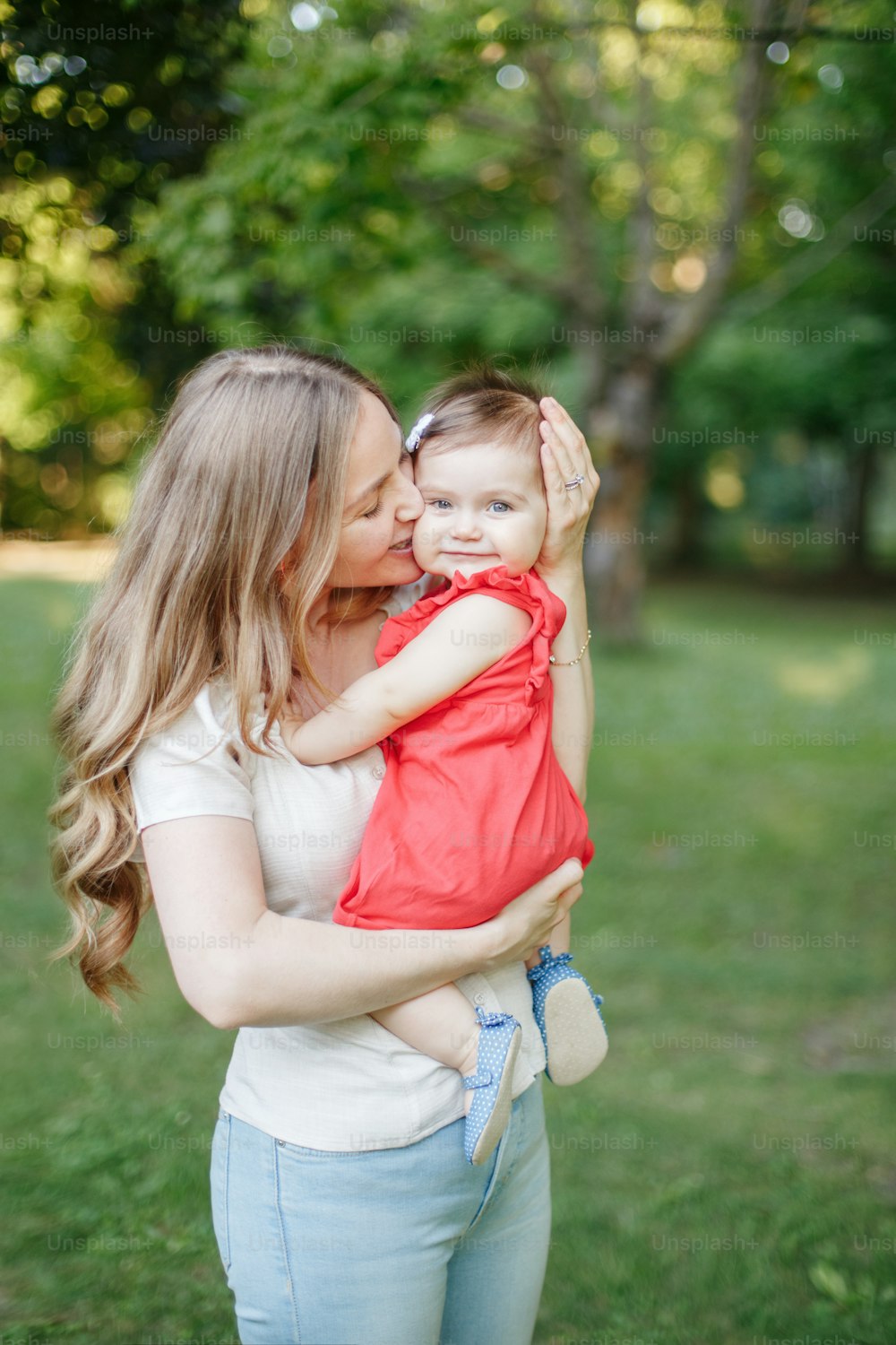 Mothers Day holiday. Young smiling Caucasian mother and girl toddler daughter hugging in park. Mom embracing child baby on summer day outdoor. Happy authentic family childhood lifestyle.