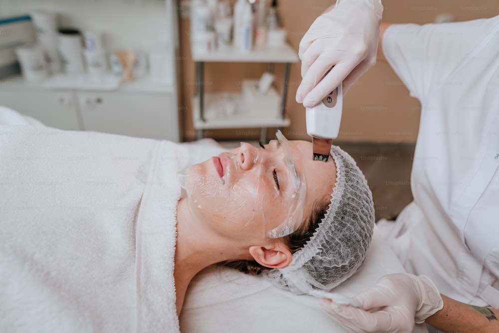 Esthetician making facial cleansing procedure using ultrasonic scin scrubber spatula in a beauty salon