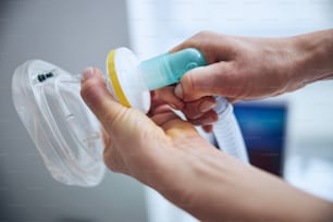투명한 플라스틱 산소 마스크를 손에 들고 있는 의사의 자른 사진